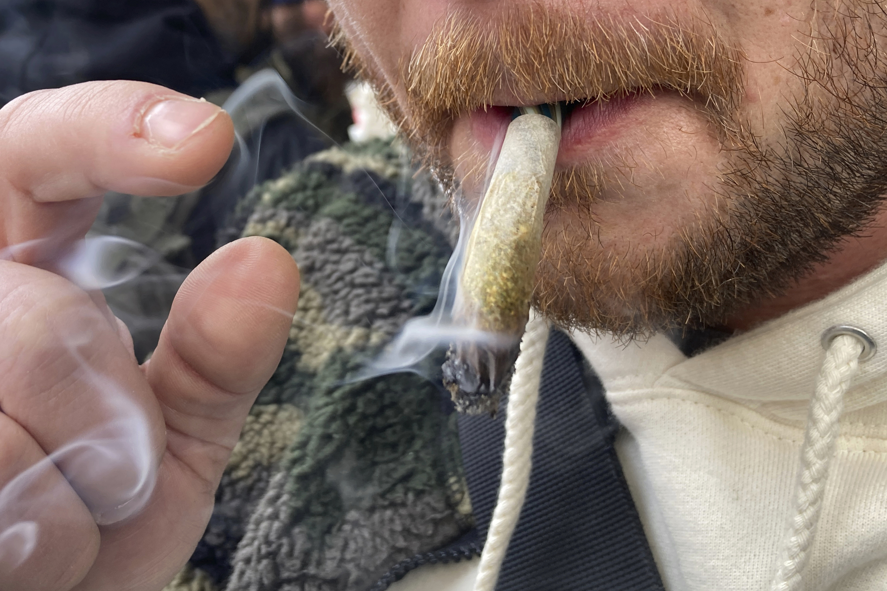 A man smokes marijuana in lower Manhattan outside the first legal dispensary for recreational marijuana in New York in December 2022. Daily and near daily marijuana use is now more common than high-frequency drinking.