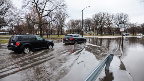 Vehicles drive on a flooded roadway on West Washington Boulevard near North Central Park Avenue in Garfield Park, Wednesday, March 11, 2026.