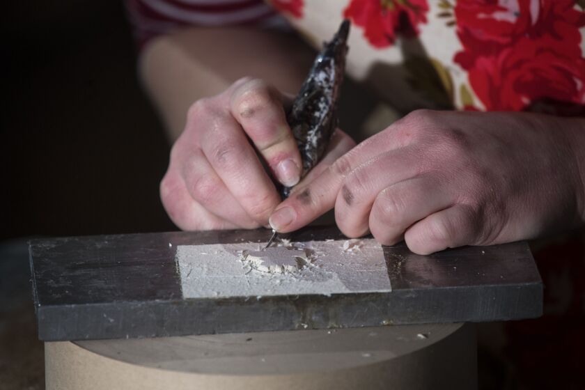 Lottie Small cuts the crests being used on the invitations for Prince Harry and Meghan Markle’s wedding in May, at the workshop of Barnard and Westwood in London Thursday March 22, 2018. Prince Harry and Meghan will get married at St George’s Chapel in Wi