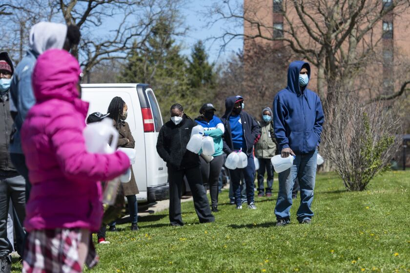 People line up outside Bronzeville Academy Charter School to receive hand sanitizer, personal protective equipment and food from volunteers with SaveMoneySaveLife and Social Change, Friday afternoon, May 8, 2020.