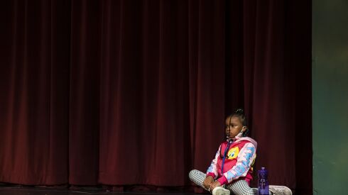 Lizzette, 6, sits off to the side as other children chat and play during Hearts to Art, a summer camp for children with parents who have died.