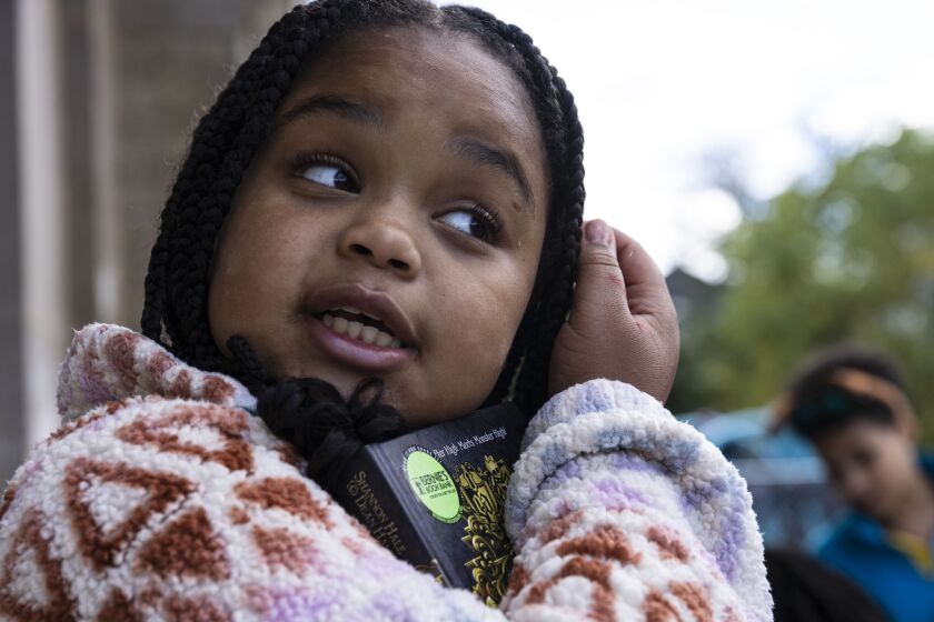 Essence Durr holds a newly received book during a Bernie’s Book Bank handout outside Jahn Elementary School at 3149 N. Wolcott Ave. Thursday, September 22, 2022.