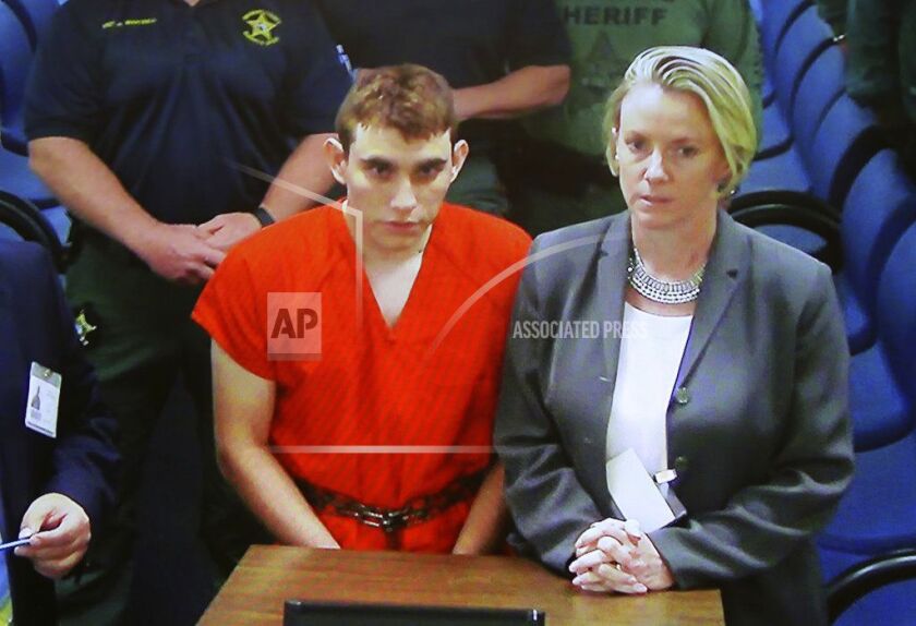 A video monitor shows school shooting suspect Nikolas Cruz, left, making an appearance before Judge Kim Theresa Mollica in Broward County Court, Thursday, Feb. 15, 2018, in Fort Lauderdale, Fla. Cruz is accused of opening fire Wednesday at the school kill