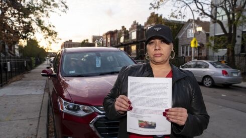 Carla Sumerlin stands near the spot where her son, Torrence, was murdered in 2020, holding up a letter she wrote and handed out to residents in the surrounding homes, asking them to come forward with tips. Police arrested two men in connection with the murder in March.