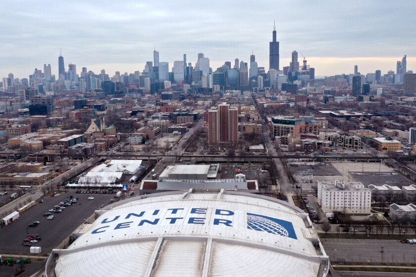 An aerial view of the United Center with the Chicago city skyline in the background.