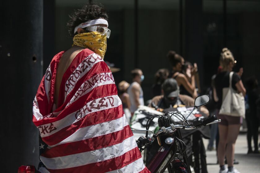 Michael Oliva, 32, wears a flag as he joined other protesters Saturday at the Boycott 4th of July rally in downtown Chicago.