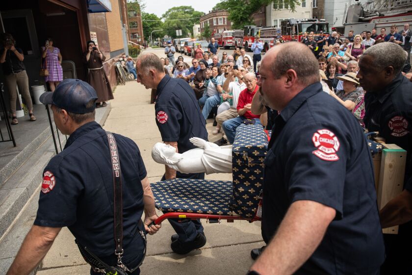 Members of the Chicago Fire Department carry the Blessed Mother statue into the newly renovated Mission of Our Lady of the Angels’ Outreach Center in the Humboldt Park neighborhood Tuesday afternoon, May 31, 2022. The Blessed Mother statue, which serves as a memorial for the victims of the 1958 fire at Our Lady of the Angels School, where 92 children and three nuns died and hundreds were injured, was blessed and installed at the outreach center Tuesday.