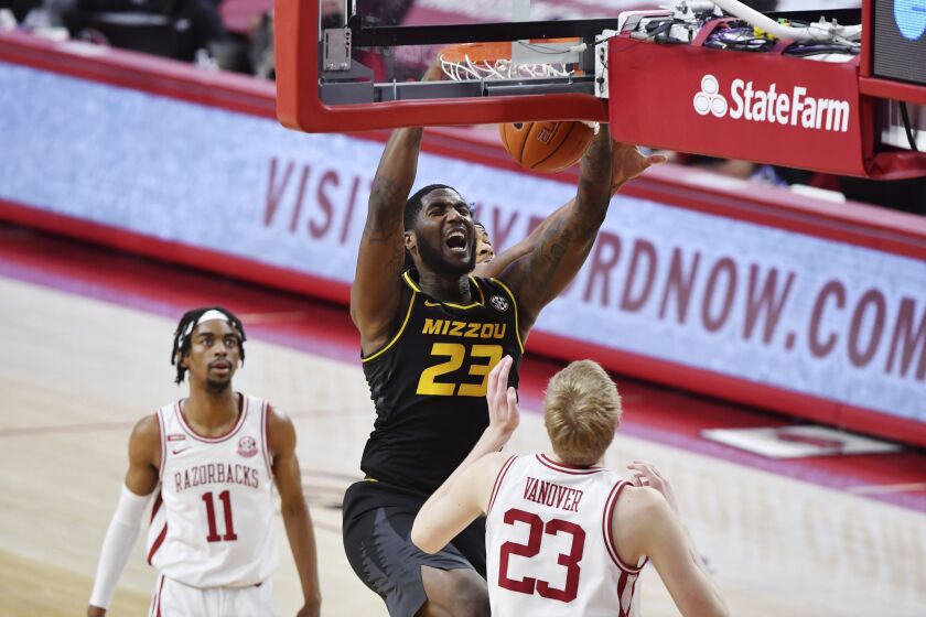 Missouri forward Jeremiah Tilmon (23) dunks the ball over Arkansas defenders Jalen Tate (11) and Connor Vanover (23).