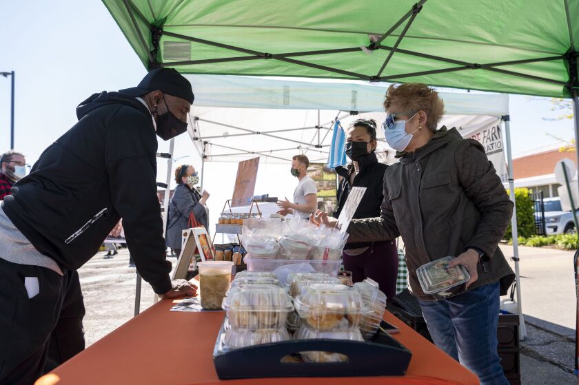 Kristine Subido, center black mask, and her mother, Melendia Subido, help a customer check out at their stall Pecking Order at the Andersonville Farmers Market, Wednesday, May 12, 2021.