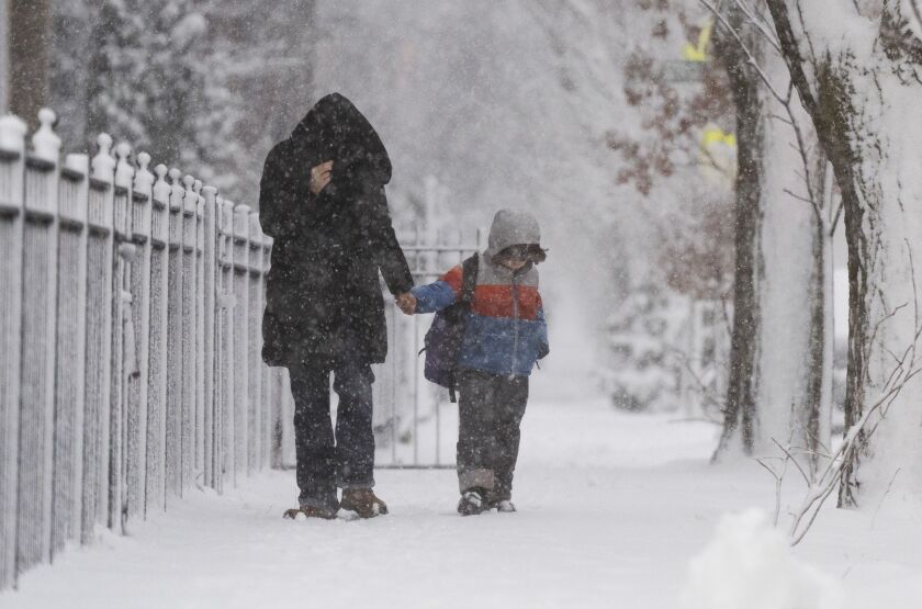 Pedestrians walk while trying to shield their faces from the wind along West Foster Avenue in the Edgewater neighborhood during a major snowstorm, Friday morning, Jan. 12, 2024.