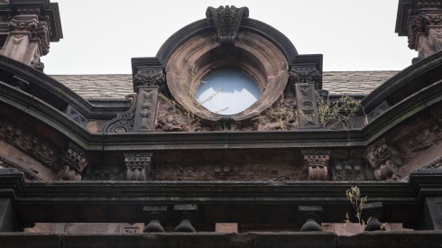 Weeds mingle with the architectural details surrounding an attic window of the O'Leary Mansion at 726 W. Garfield Blvd.