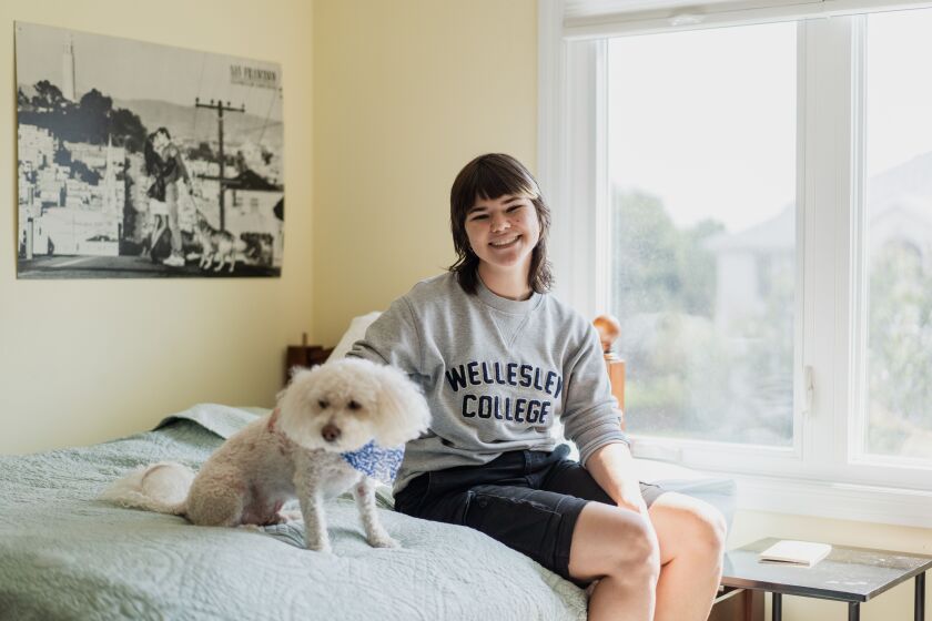Bridget Lynch, 21, an incoming junior majoring in geosciences at Wellesley College in Massachusetts, sits with her dog, Finn, in her room in Orland Park on Wednesday, saying she feels “lighter” after hearing that President Joe Biden is canceling between $10,000 and $20,000 in federal student loans for qualifying students. Lynch says about a third of her student loans will be reduced.