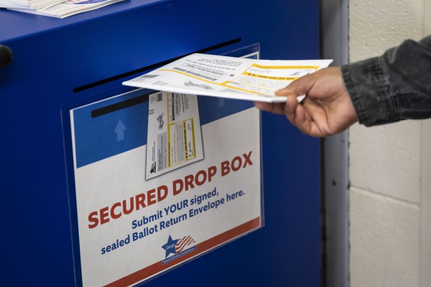 An early voter drops a mail-in ballot in the secured drop box at Warren Park in the West Rogers Park neighborhood on Wednesday.