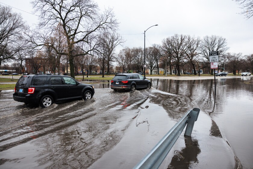 Vehicles drive on a flooded roadway on West Washington Boulevard near North Central Park Avenue in Garfield Park, Wednesday, March 11, 2026.
