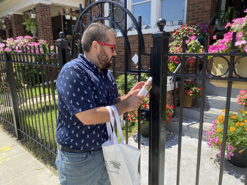 Angel Lorenz, volunteer with the Southwest Organizing Project, leaves census flier on an iron-rod fence in Chicago Lawn on August 4, 2020. Manny Ramos/Sun-Times
