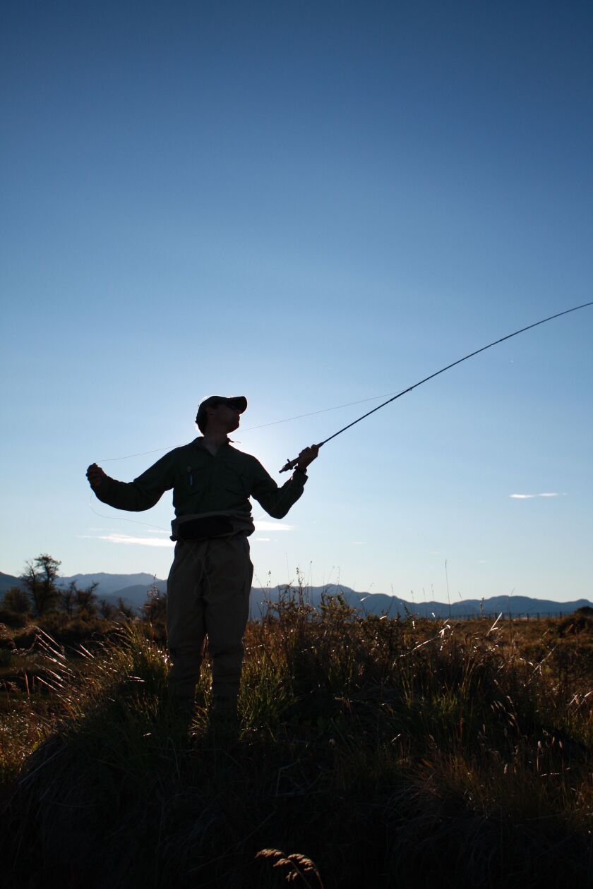 A fly caster is highlighted alone against the sky in Patagonia.<br>Credit: Cameron Chambers