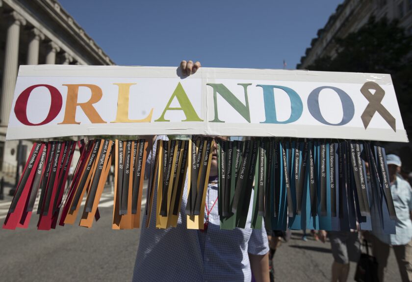Gil Mendez of San Francisco holds a sign to honor the victims of the shooting at the Pulse Nightclub in Orlando, Florida, as he marches during the Equality March for Unity and Pride in Washington on Sunday. | Carolyn Kaster/Associated Press