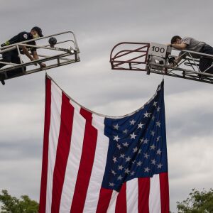 Chicago Fire Department personnel hang the American flag outside the Cook County medical examiner’s office for the procession for Deputy Chief Dion Boyd, who was found dead in his office Tuesday morning, July 28, 2020. Boyd died of an apparently self-inflicted gunshot wound.