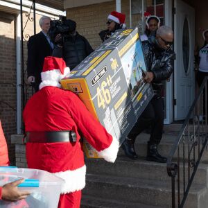Volunteers bring presents inside a house in Englewood during an early Christmas Eve event to surprise the children of two mothers killed while working as peacemakers in Chicago.