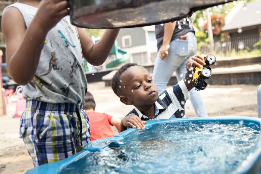 Jaxson Kirkendall, 2, plays with a yellow toy monster truck in a small tub of water at Bixler Park in Hyde Park.