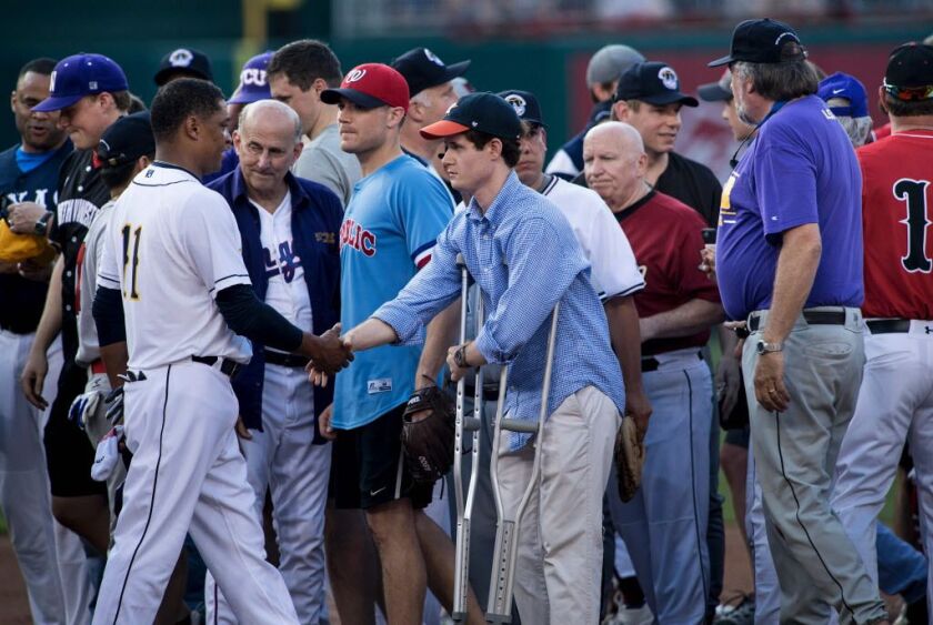 Congressional staff member Zack Barth (on crutches), who was wounded in Wednesday’s shooting, is greeted by the Democrat’s pitcher Rep. Cedric Richmond (left), D-La., before the Congressional Baseball Game between Democrats and Republicans at Nationals St