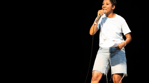 Briana Mathews, manager of youth development at My Block, My Hood My City, speaks to a crowd of teens at Harris Theater.