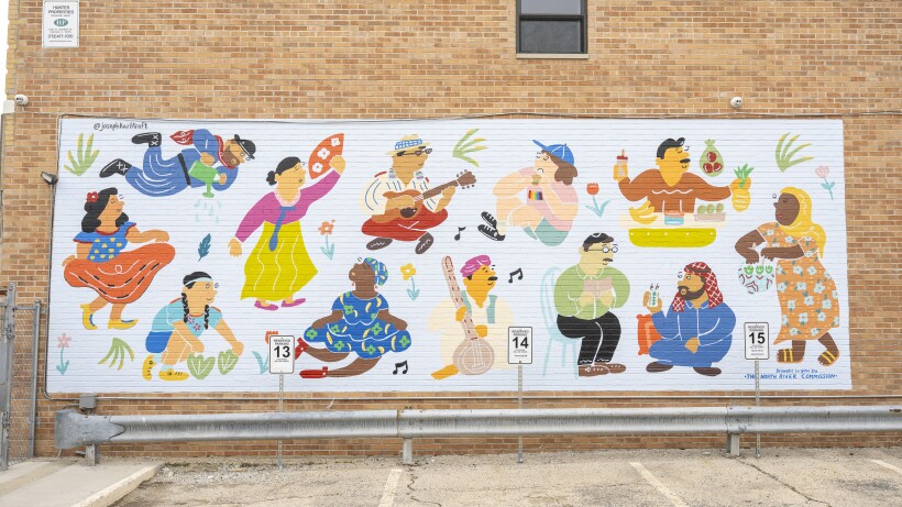 A mural on a brick building shows 12 people from various cultures.