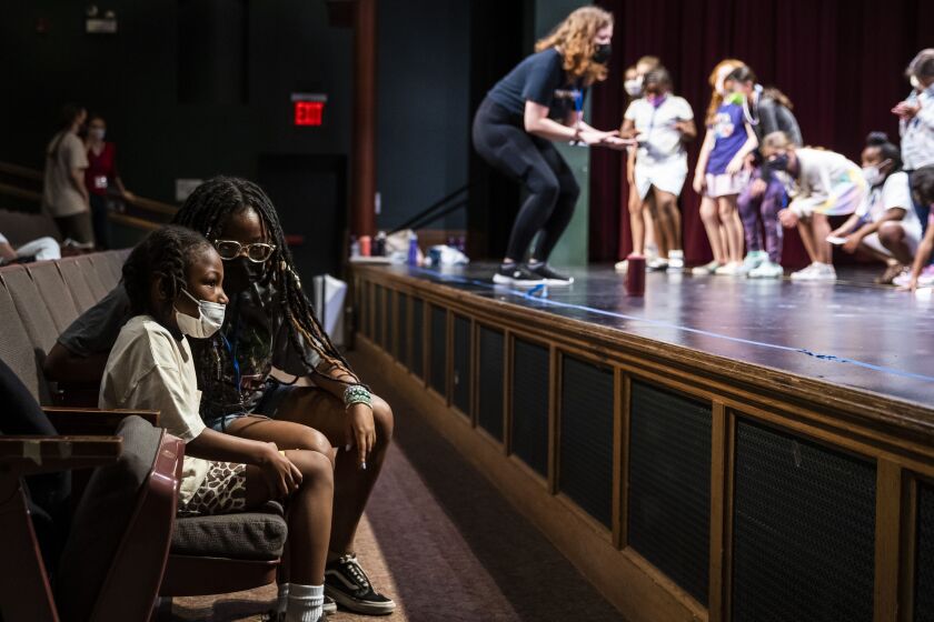 Junior counselor Noelle Hutchinson talks with 6-year-old Davion as other students play and dance during Hearts to Art, a summer camp at the Vittum Theater on July 11, 2022.