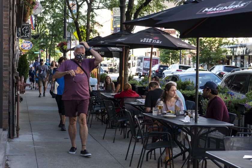 People dine outside at Wilde Bar & Restaurant as others walk along the sidewalk in June.
