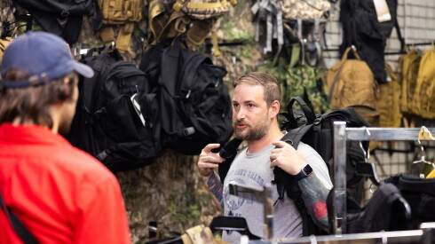 Army Navy Sales owner Adam Hirsch helps a customer find gear for an upcoming hiking trip.