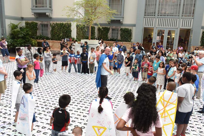 David L. Hoyt (center) explains his “Word Winder” game to a group of students in the Winter Garden at the Chicago Public Library’s Harold Washington Library Center. Hoyt met puzzle-maker Riya Joshi at the event in July of 2017.