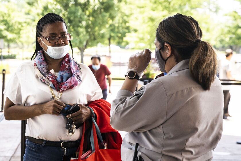 A security guard stationed at the front door tells a woman to pull her face mask up over her nose before she can enter Rivers Casino in Des Plaines in July.