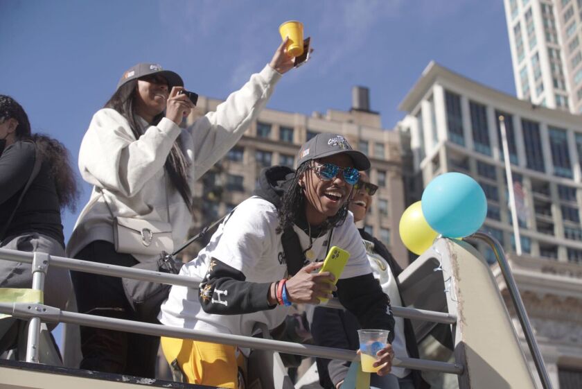 Diamond DeShields leans over the railing of her bus to greet fans as she and other Chicago Sky players enjoy the ride up Michigan Avenue to the Millennium Park rally.