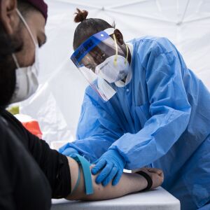 Phlebotomist Crystal Bovan, with Simple Laboratories, draws blood for coronavirus antibody testing for a man at the lab’s drive-thru testing site in the parking lot of St. Rosalie Catholic Parish in Harwood Heights, Friday, May 1, 2020.