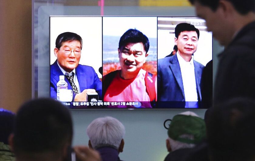 People watch a TV news report on screen, showing portraits of three Americans, Kim Dong Chul, left, Tony Kim and Kim Hak Song, right, detained in the North Korea, at the Seoul Railway Station in Seoul, South Korea. | AP file photo