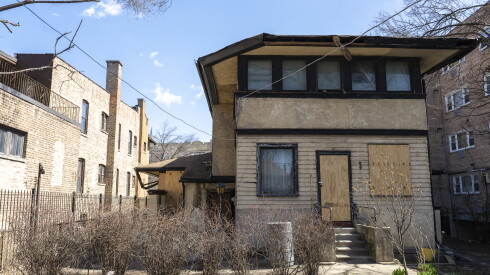 A rear view of the deteriorating J. J. Walser Jr. House in Austin, with the back door and a window boarded up.