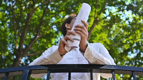 A person holds a rolled stack of insurance company correspondence and medical documents.