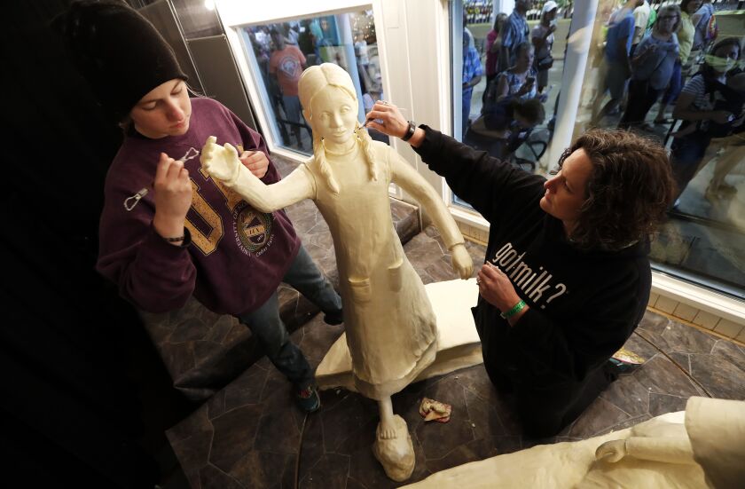 In this Thursday, Aug. 10, 2017, photo, Sarah Pratt works on a butter sculpture of author Laura Ingalls Wilder with her daughter Grace (left) at the Iowa State Fair in Des Moines, Iowa. | AP Photo/Charlie Neibergall