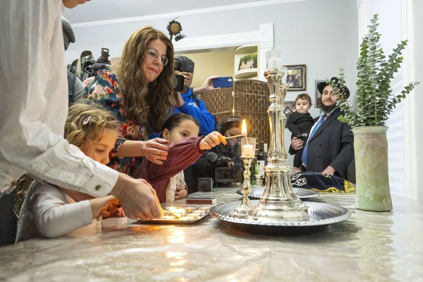 Yehudis Hecht guides children into lighting candles for the Jewish Sabbath in her Evanston home, Friday, Oct. 20. Hecht is good friends with Judith and Natalie Raanan, who were held hostage and released by Hamas.