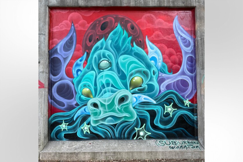 A teal creature that looks like a buffalo with purple horns appears on mural on a railroad embankment on Hubbard Street in West Town.