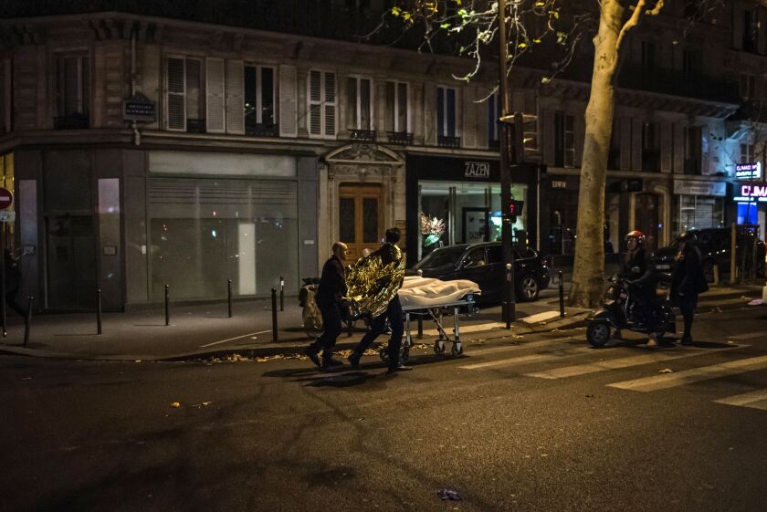 A victim is being evacuated from the Bataclan concert hall after a shooting in Paris. | Kamil Zihnioglu/Associated Press
