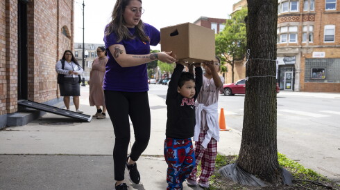 Antonella, 8, and Tadeo, 3, help workers load the family’s van with boxes of groceries from the El Hogar Del Niño food pantry.