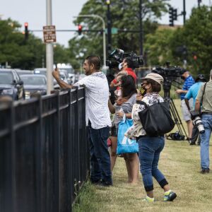 People and members of the media watch from a nearby park as Chicago Police investigate at the 25th District station, 5555 W. Grand Ave., on the Northwest Side, after multiple officers were shot outside the station, Thursday morning, July 30, 2020. The suspect was also shot multiple times in the incident.