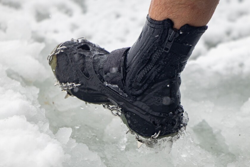 George Miller wears crampons on his boots as he wades out into an icy Lake Michigan at Oak Street Beach, Sunday, Jan. 25, 2026. | Candace Dane Chambers/Sun-Times.