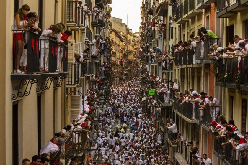 People watch as Jandilla fighting bulls and revelers run during the running of the bulls at the San Fermin festival in Pamplona, Spain, Tuesday, July 7, 2015. Revelers from around the world arrive to Pamplona every year to take part in some of the eight d