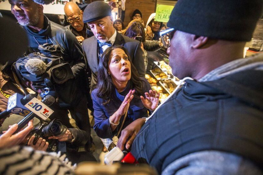 Camille Hymes, center, regional vice president of Mid-Atlantic operations at Starbucks Coffee Company, speaks with Asa Khalif, of Black Lives Matter, right, after protesters entered the coffee shop, Sunday, April 15, 2018, demanding the firing of the mana