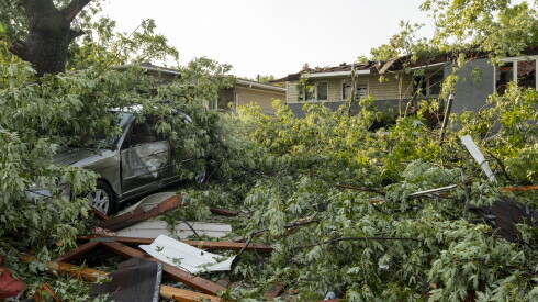 A vehicle that was pushed into a tree and other tree debris litter a severely damaged home near 192nd Place and Oakwood Avenue after severe storms and high winds hit far south suburban Lansing, Monday, July 27, 2026.