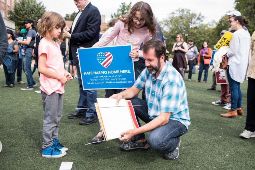 Martin Perdoux, with his daughters Alice Favorite-Perdoux and Lucille Favorite-Perdoux, prepare a Black Lives Matte sign to be posted on their lawn before a rally Sunday at Waters Elementary School. | Max Herman/For the Sun-Times