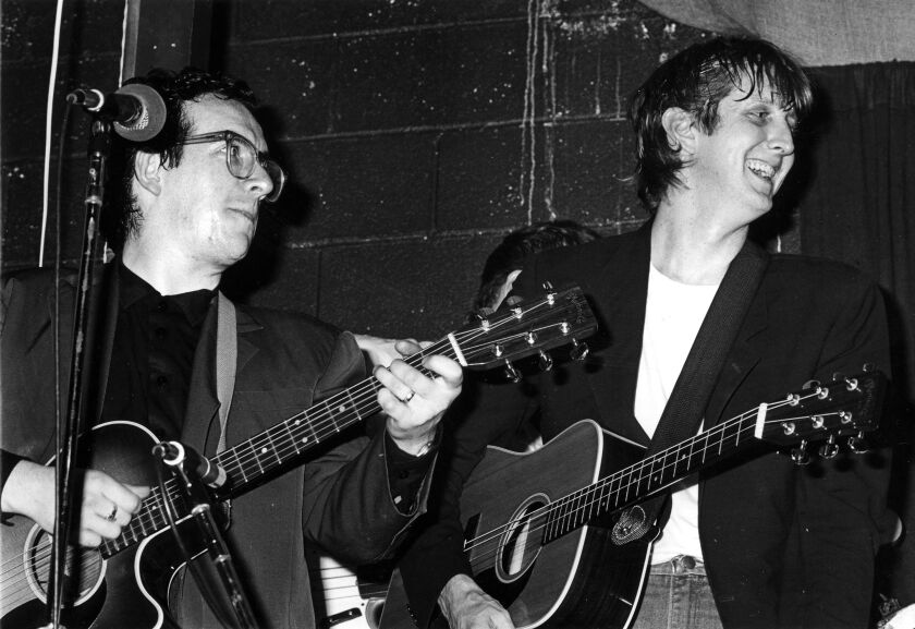 T Bobe Burnett with Elvis Costello at McCabe’s Guitar Shop, Santa Monica, California, 1984. | Photo by Sherry Rayn Barnett/From “T Bone Burnett: A Life in Pursuit” (copyright © 2016 by Lloyd Sachs), published by the University of Texas Press.