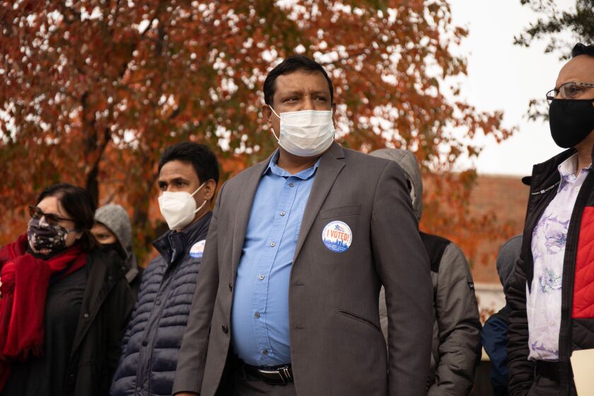 Nasir Zakaria, director of Rohingya Culture Center, in brown coat, stands outside the Warren Park Field House, an early voting site, after voting in the West Rogers Park neighborhood Tuesday afternoon.
